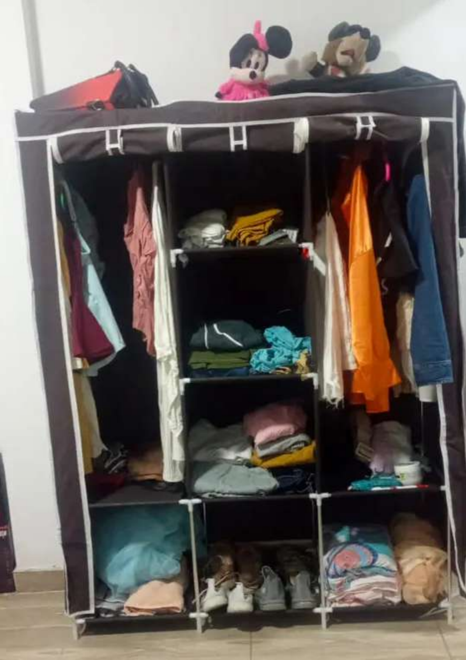 Armario negro lleno de ropa, prendas colgadas y zapatos